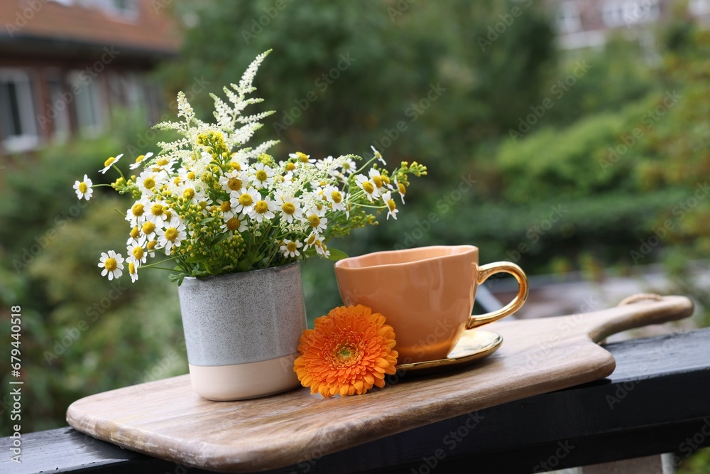 Cup of delicious chamomile tea and fresh flowers outdoors Cup of delicious chamomile tea and fresh flowers outdoors