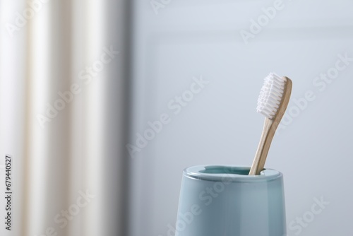 Bamboo toothbrush in holder on blurred background, closeup. Space for text