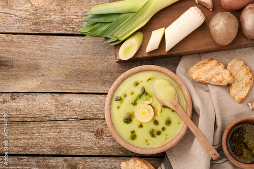 Delicious leek soup on wooden table, flat lay. Space for text