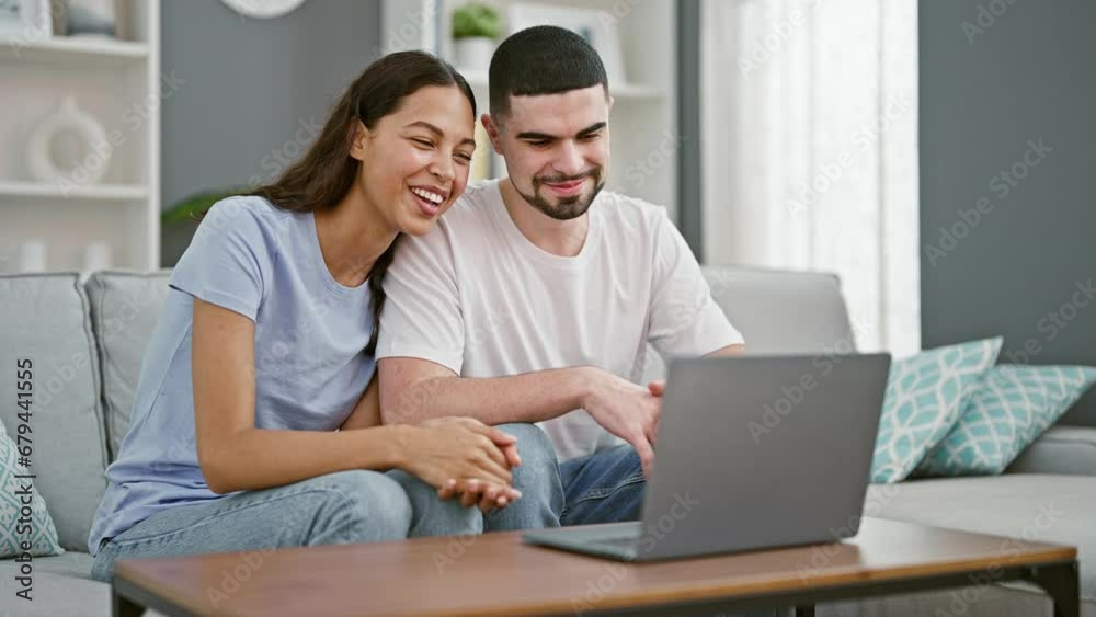Beautiful couple having video call sitting on sofa smiling at home Beautiful couple having video call sitting on sofa smiling at home