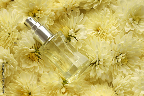 Women fragrance perfume bottle with flowers background close up. Unnamed blank sprayer bottle of perfume for women photo