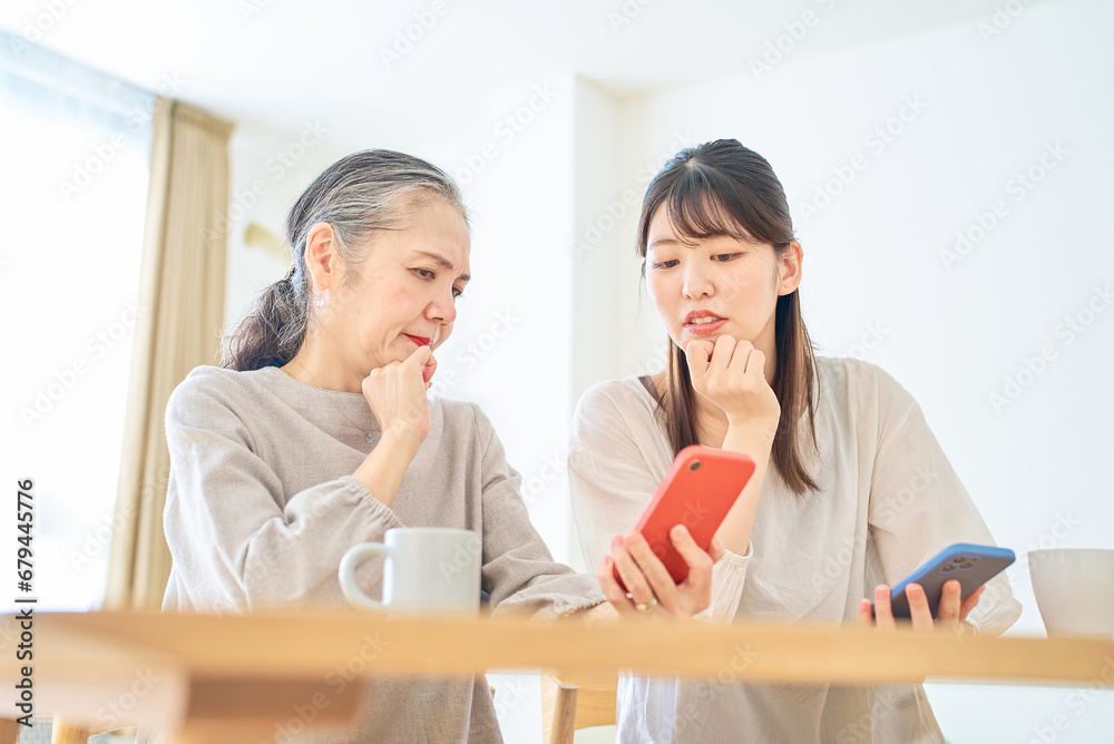 スマートフォンの画面を心配そうに見るシニア女性と若い女性