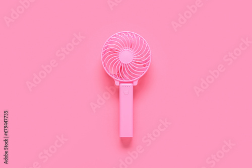 Modern manual fan on pink background photo
