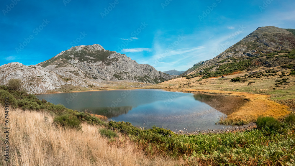 Lake of glacial origin on a sunny day with blue skies, situated between meadows and mountains in the north of León, Spain.