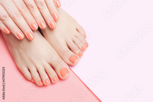 Female hands and feet with manicure and pedicure on pink background close-up  top view.