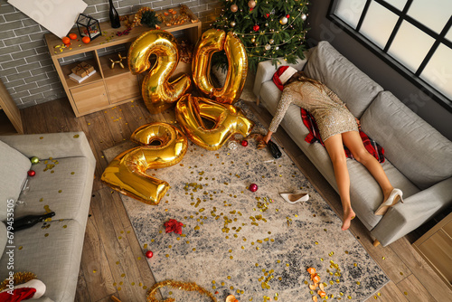 Drunk woman lying on sofa in messy living room after New Year party photo