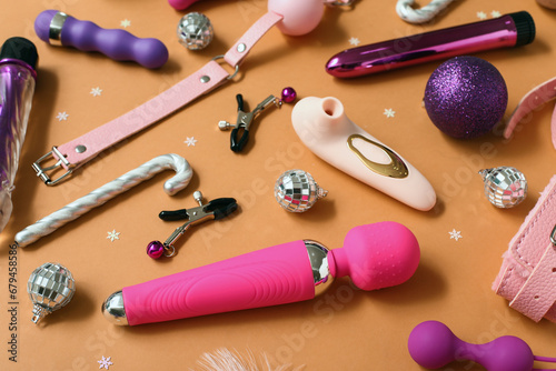 Different sex toys and Christmas decor on orange background