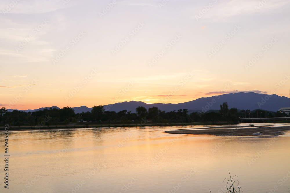 Aerial panoramic landscape with evening sunset over the river with islands and beautiful mountain clouds on golden yellow sky.