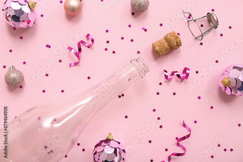 Champagne bottle with Christmas decor on pink background