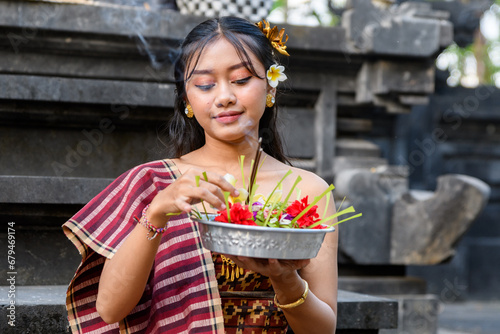 Young woman in traditional clothing making an offering at a temple