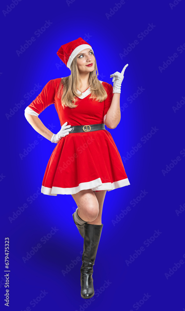 Young woman dressed as Santa Claus at Christmas pointing a space for advertising with her finger on blue background Young woman dressed as Santa Claus at Christmas pointing a space for advertising with her finger on blue background