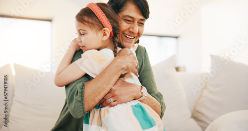 Grandmother, child and hug on sofa in living room for love, care and bond for relationship. Senior woman, little girl and smile in happiness for memory, moment or support while babysitting at home photo