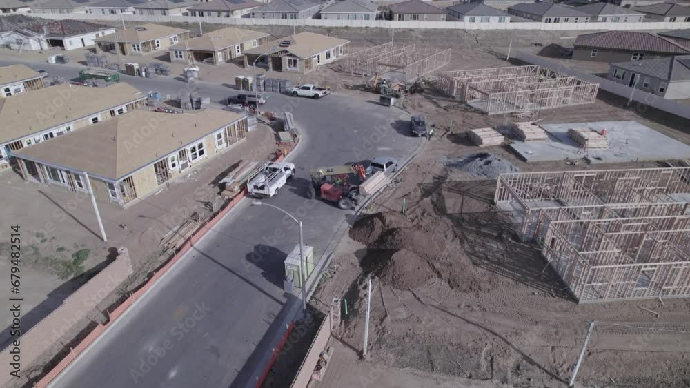 A circling drone captures an extendable forklift (telehandler) in action, gently lowering a load of wood on a home construction site within a new neighborhood A circling drone captures an extendable forklift (telehandler) in action, gently lowering a load of wood on a home construction site within a new neighborhood
