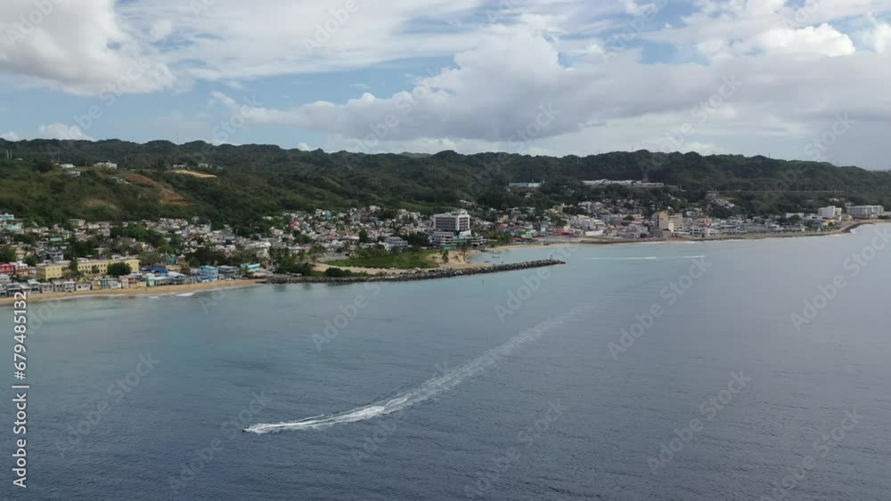 High drone footage of speedboat sailing near to Rompeolas Beach in Aguadilla, Puerto Rico