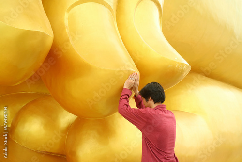 Man Touching the Finger of the Great Buddha Image for the Blessing, Wat Muang Temple, Ang Thong Province, Thailand photo