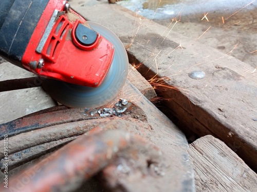 A special plow for digging potatoes is cleaned with a Bulgarian. Repair of agricultural equipment. Sparks when working with metal. photo