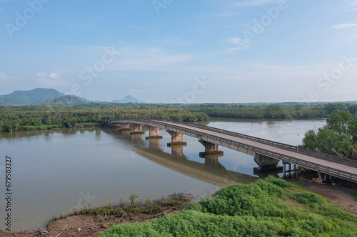 Aerial top view of a bridge with garden park with green mangrove forest trees, river, pond or lake. Nature landscape background, Thailand.