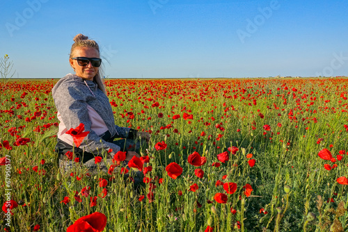 A woman on the background of a poppy field in the Crimea. A beautiful field of wild red poppies at sunset in the evening. Sunset over a poppy field in the countryside.