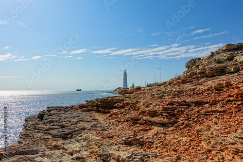 Lighthouse on Cape Tarkhankut. The rocky coast of the Dzhangul Reserve in the Crimea. Turquoise sea water. Tarkhankutsky lighthouse on the Crimean peninsula. photo