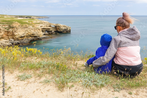 A girl with a child on Cape Tarkhankut. The rocky coast of the Dzhangul Reserve in the Crimea. Turquoise sea water. Rocks and grottoes of Cape Tarkhankut on the Crimean peninsula.