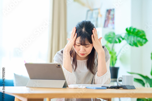 部屋でパソコン操作中にストレスを感じる女性