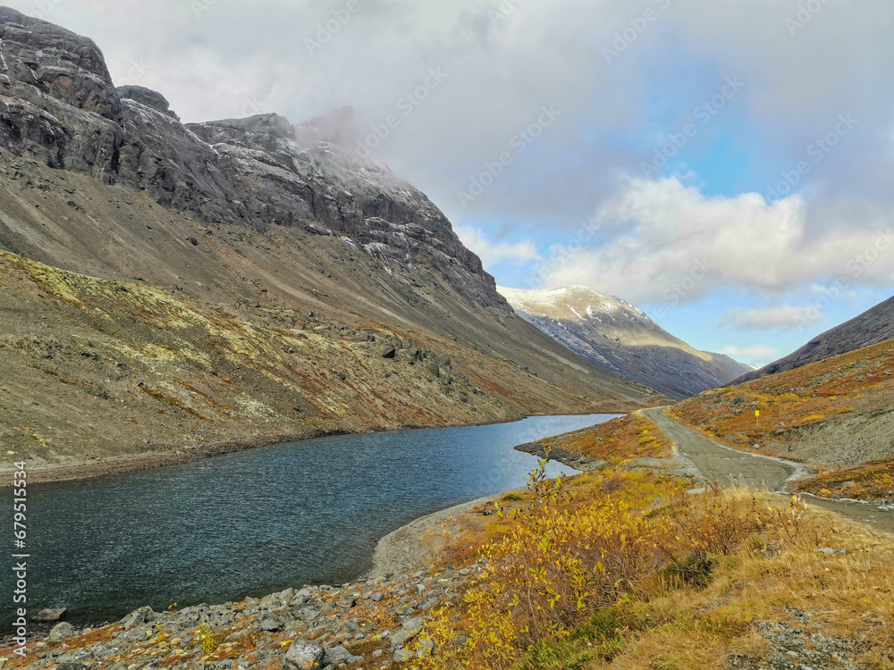 Golden autumn in the Arctic mountains beyond the Arctic Circle. View of a beautiful lake and yellow birches. Mountain peaks in the background. Autumn in the mountains of Khibiny.