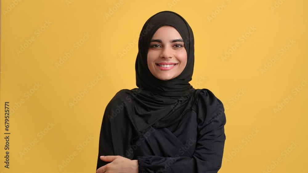 Cute young Turkish woman in traditional black headscarf smiling posing isolated on orange background Cute young Turkish woman in traditional black headscarf smiling posing isolated on orange background