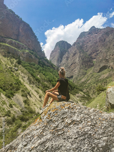 A girl on the background of the picturesque gorge of the Jylgy-su river. The Caucasus Mountains near the ancient city of Eltuby. Next to the grotto with an ancient human parking lot.