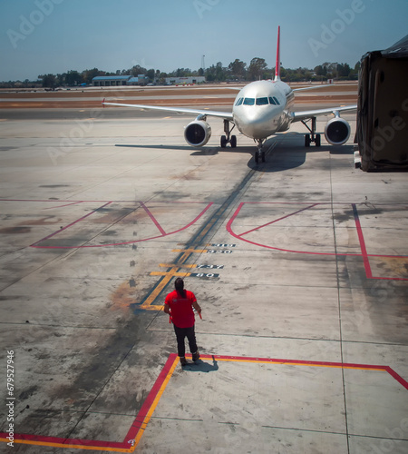 Marshaller directing commercial airliner to park at terminal photo