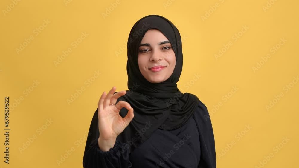 Beauty Turkish woman in black headscarf gesturing ok okay cool approve posing isolated orange studio Beauty Turkish woman in black headscarf gesturing ok okay cool approve posing isolated orange studio