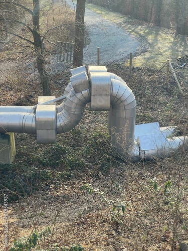 Shiny metal pipes situated in a densely forested area surrounded by lush vegetation © Wirestock