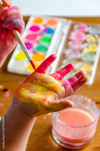 Kinderhand mit Pinsel und Wasserfarbe photo