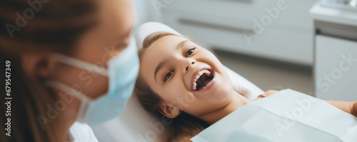 Little cute girl sitting in dental chair while doctor fixing her teeth. Dental care concept photo
