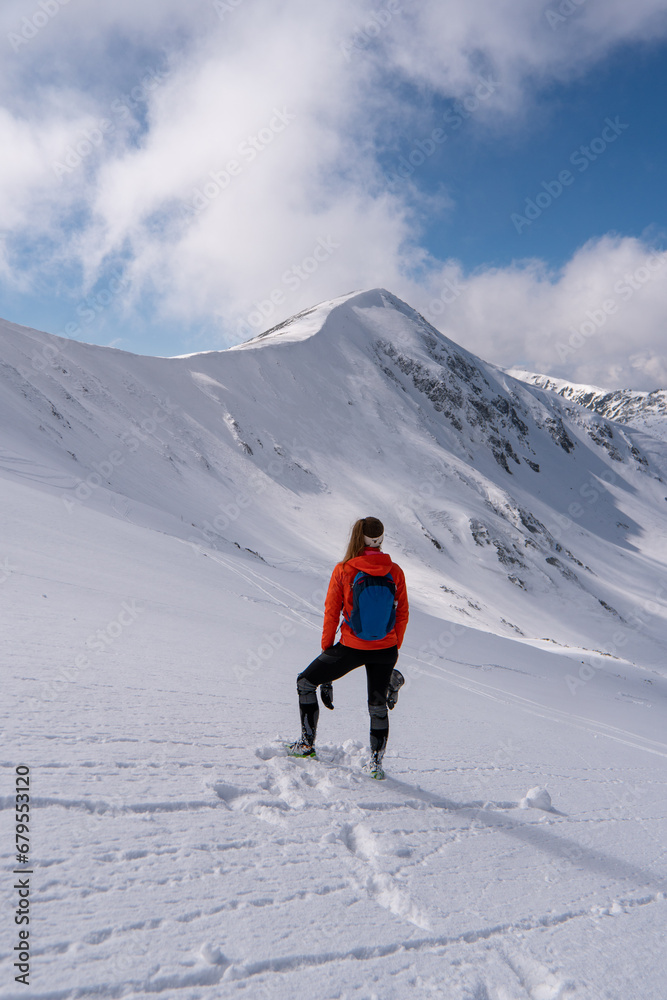 Woman mountaineer during a descent with crampons on snowy slope. Young woman admiring the view at Low Tatras, in tatras mountain in Slovakia Europe