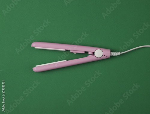 Mini Hair straightener on green background. Top view