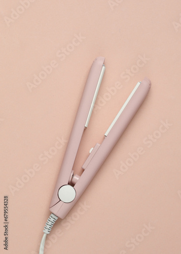 Mini hair straightener on a pink background. Top view