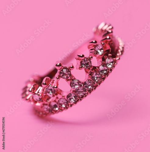 Golden ring crown floating on pink background with shadow