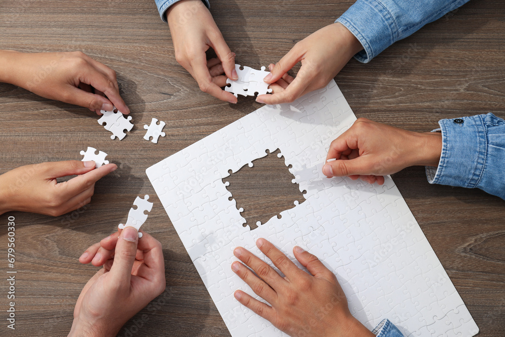 White puzzles and hands on wooden background White puzzles and hands on wooden background