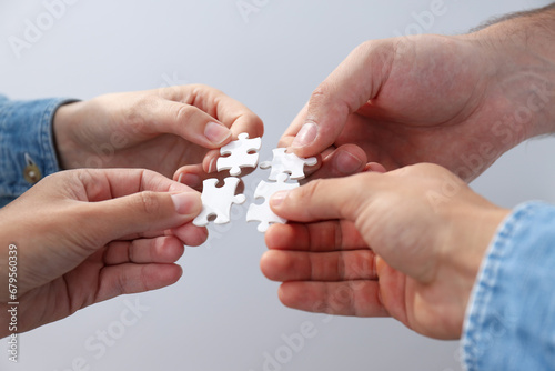 White puzzles in hands on light background, close up