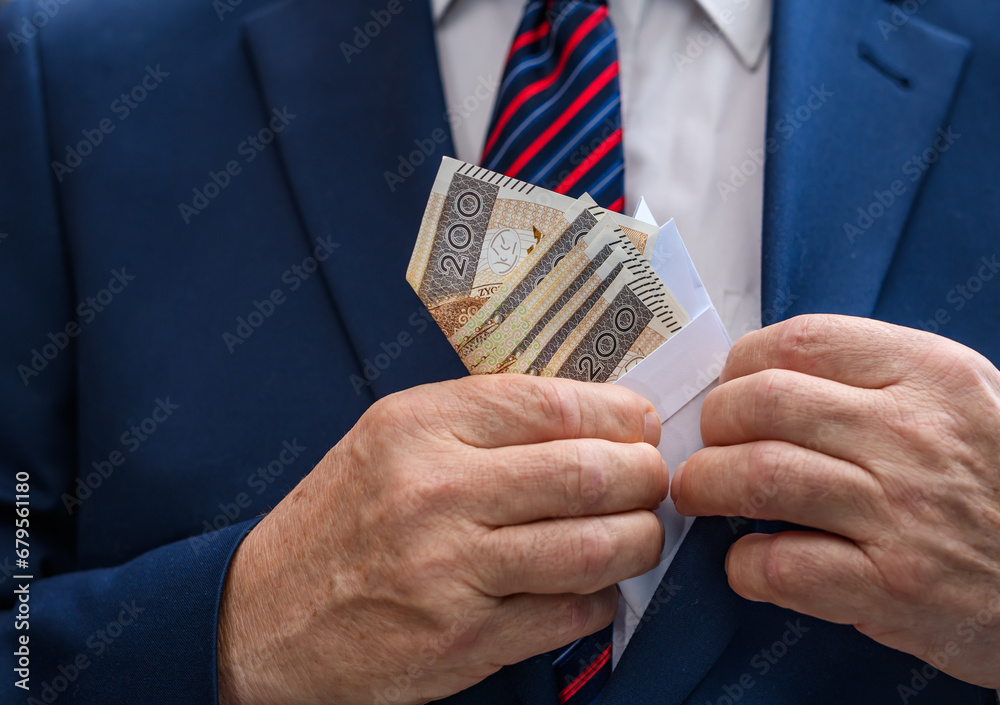 Człowiek w eleganckim garniturze chowa kopertę z pieniędzmi do kieszeni w marynarce  - obrazy, fototapety, plakaty 