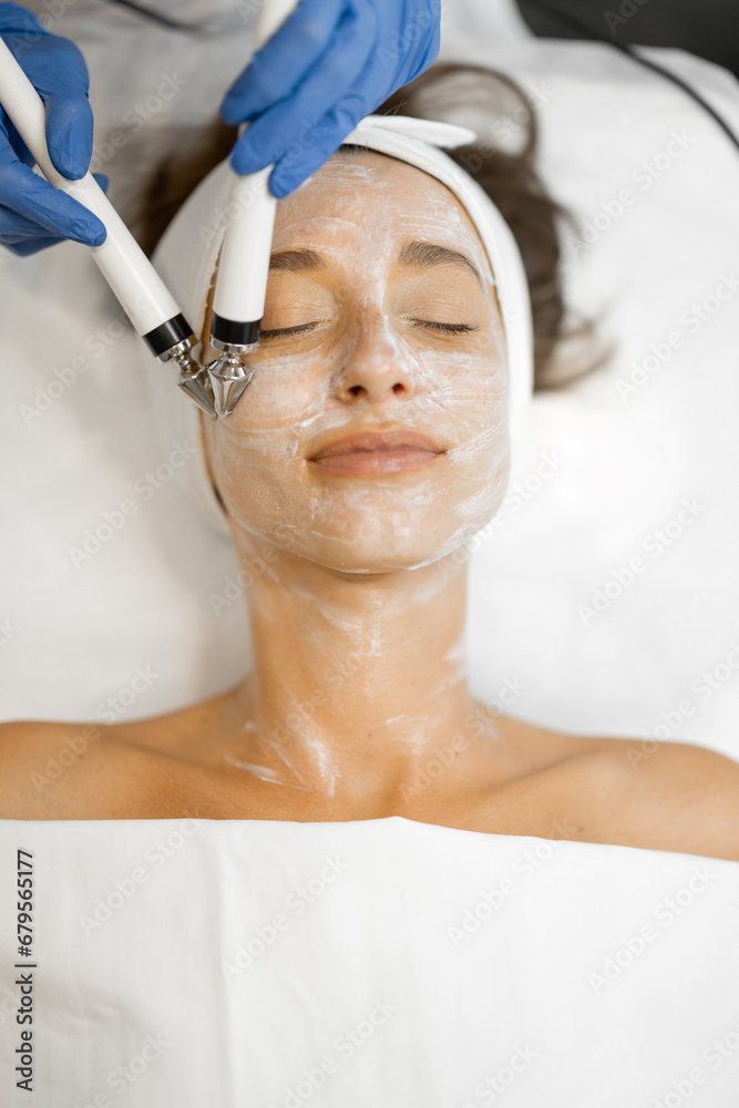 Young woman during facial microcurrent procedure, view from above on