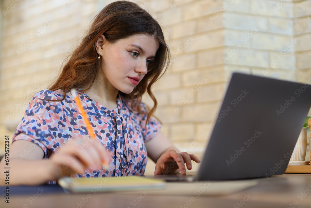 A young woman working on a laptop, embodying a modern, digital lifestyle in a casual setting. A young woman working on a laptop, embodying a modern, digital lifestyle in a casual setting.