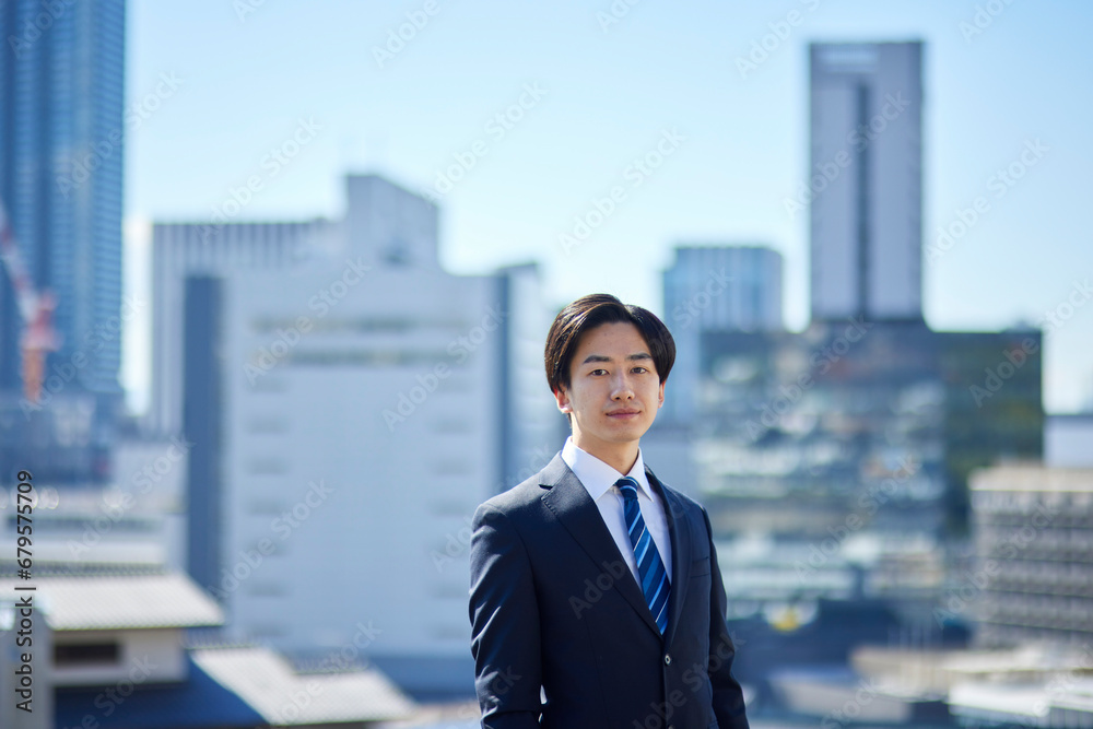 スーツを着た若い日本人ビジネスマンと町並み スーツを着た若い日本人ビジネスマンと町並み