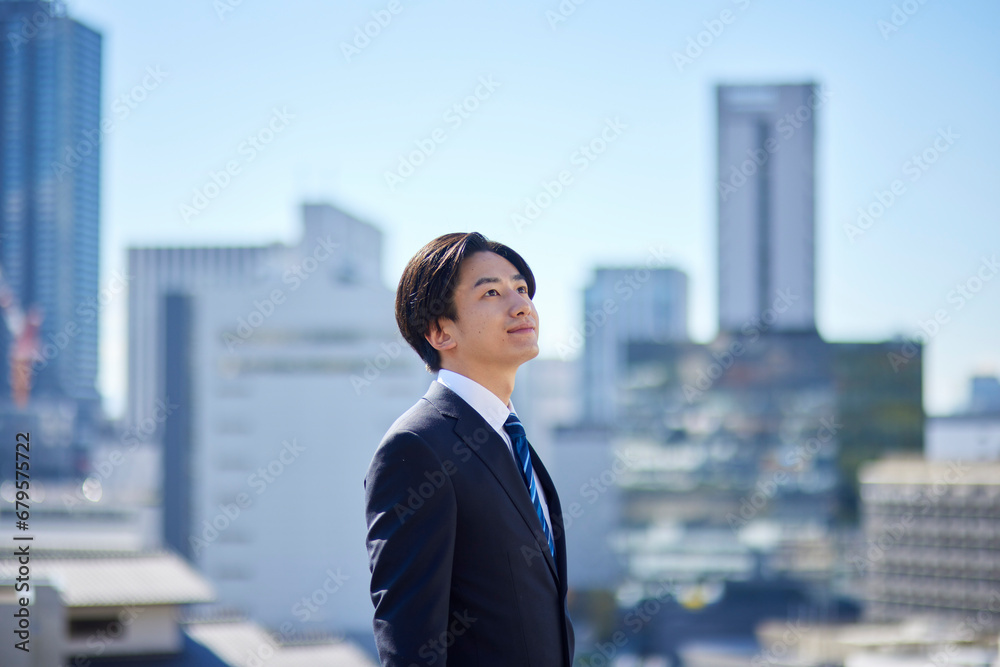スーツを着た若い日本人ビジネスマンと町並み スーツを着た若い日本人ビジネスマンと町並み