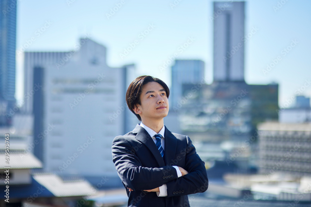 スーツを着た若い日本人ビジネスマンと町並み
