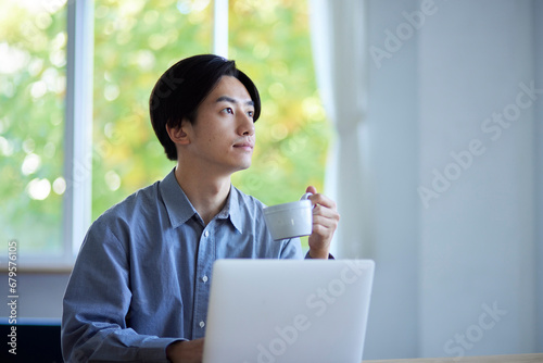 リビングでパソコンを使用する日本人大学生の男性 photo