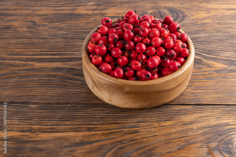red hawthorn berries in wooden bowl on flat wooden surface red hawthorn berries in wooden bowl on flat wooden surface