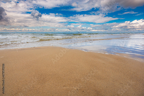 Beautiful landscape with coastline of sandy beach and stormy sea with cloudy sky over it photo