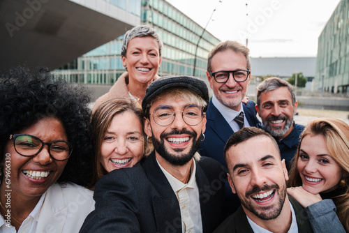 Multicultural business team in a meeting taking a selfie outdoor. Businessmen and businesswomen posing for a photo together. Teamwork people smiling and laughing to the camera
