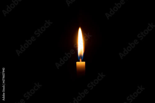 A single burning candle flame or light glowing on an orange candle on black or dark background on table in church for Christmas, funeral or memorial service with copy space